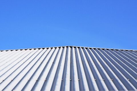 Corrugated metal roofing on a house with a blue sky behind it by Bryan Exteriors